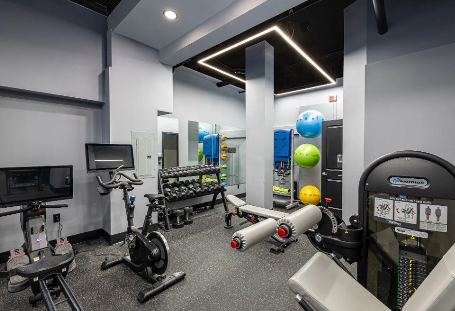A gym with a variety of equipment including treadmills, stationary bikes, and weight machines.